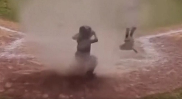 Un niño queda atrapado en un remolino de polvo durante un partido de béisbol